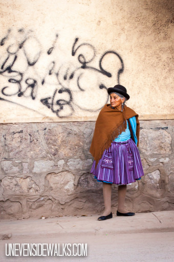 Indigenous lady in Bolivia Standing on the Uneven Sidewalk
